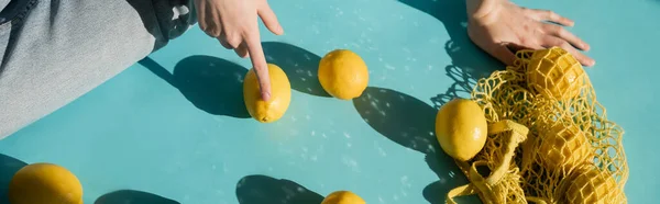 Обрезанный Вид Женщины Сидящей Рядом Мешком Спелыми Лимонами Голубом Баннер — стоковое фото