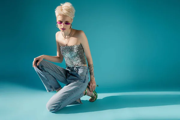 ピンクのサングラスと青を基調とした流行の衣装でタトゥーの入ったアルビノモデルの全長 — ストック写真