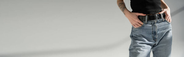 обрезанный вид женщины в джинсах в джинсах, позирующей на сером фоне, баннер 
