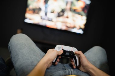 KYIV, UKRAINE - 13 Şubat 2023: Oyun kulübünde bulanık televizyonun yanında oynayan genç adamın görüntüsü 