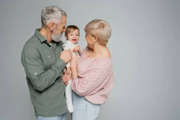 Middle Aged Couple Holding Hugging Cheerful Granddaughter Isolated Grey — Stock Photo, Image