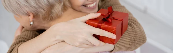 Gedeeltelijk Uitzicht Glimlachende Vrouw Met Rode Geschenkdoos Omarmen Van Middelbare — Stockfoto
