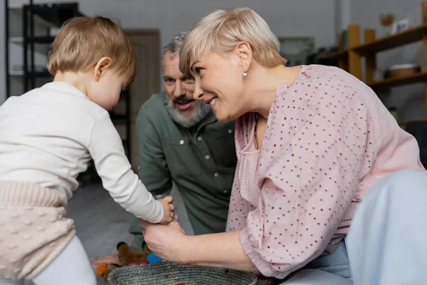 Glad Kvinna Och Skäggig Man Leker Med Lilla Barnbarn Hemma — Stockfoto