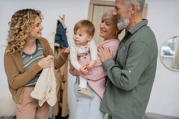 счастливая пара средних лет, встречающая взрослую дочь с маленьким ребенком дома