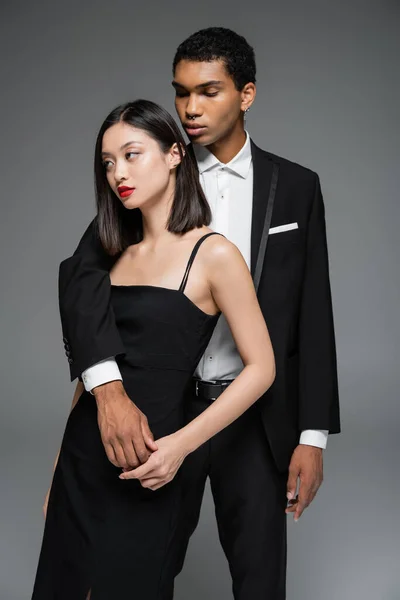 Hombre Afroamericano Moda Abrazando Mujer Asiática Traje Elegante Negro Mirando —  Fotos de Stock