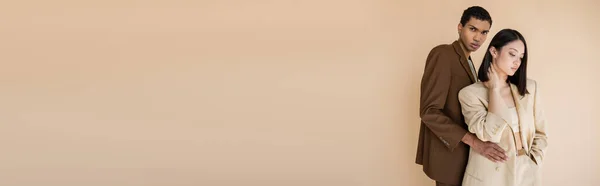 Афроамериканський Чоловік Стильному Блістері Обіймає Чуттєву Азіатську Жінку Ізольовано Бежевому — стокове фото