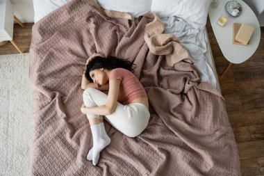 Evde pijamalı depresif bir kadın yatağında yatıyor. 