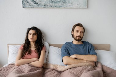 Evde yatakta otururken kollarını kavuşturmakta zorlanan bir çift. 