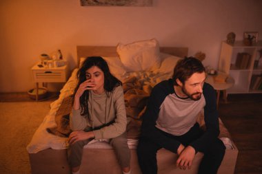 Tatminsiz kadın gece yatakta erkek arkadaşının yanında oturuyor. 
