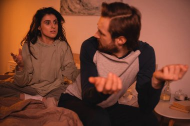 Stresli bir kadın gece yatak odasında bulanık erkek arkadaşıyla tartışıyor. 