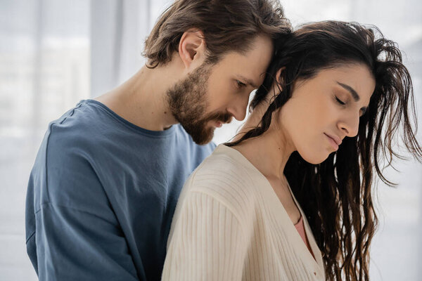 Bearded man standing near brunette girlfriend at home 