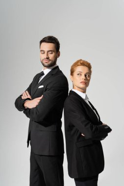  Siyah takım elbiseli, güvenilmez iş adamları sırt sırta verip kollarını katlayarak gri renkte izole ediyor.