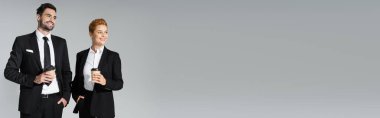 Mutlu iş ortakları ellerinde kağıt bardaklar ve gözlerden uzak gri pankarta bakıyorlar.