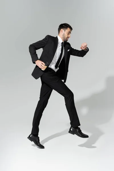 スタイリッシュなスーツを着たビジネスマンの長時間のチェックと灰色の背景での浮揚 — ストック写真