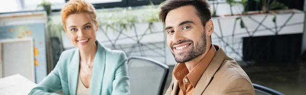 成功的商业伙伴穿着时髦的西装 对着办公室里的相机微笑 高举横幅 — 图库照片