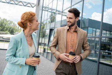 Şık yöneticiler birbirlerine gülümserken, şehir caddesinde ellerinde içkilerle dolaşıyorlar.