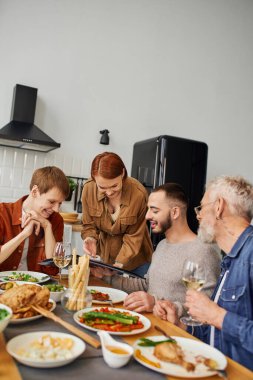 Çocukları olan bir aile evde yemek pişirirken oturup gülümsüyor.
