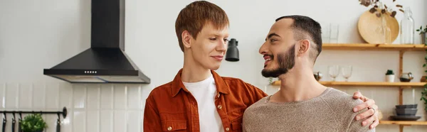 若い陽気なゲイのカップルがキッチンやバナーで笑顔で — ストック写真