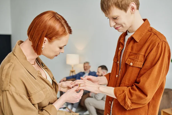 快乐的男同性恋在家里向红头发的母亲展示结婚戒指 — 图库照片