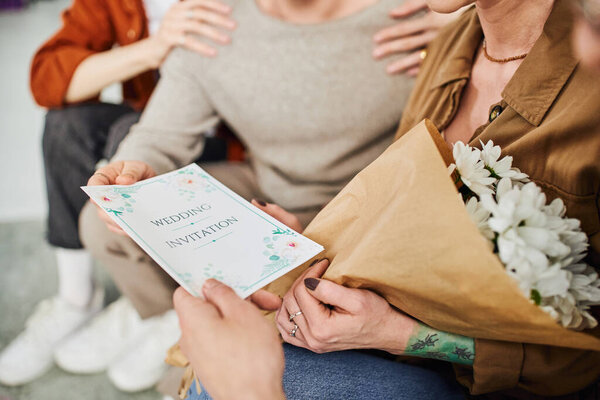 selective focus of wedding invitation near young gay couple and parents sitting at home