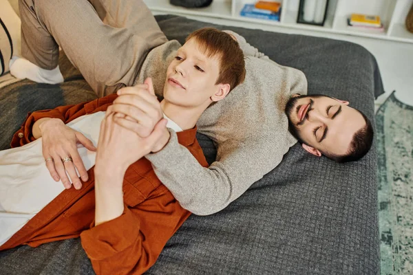 自宅のベッドに横になって手をつないでいる同性カップルの高い角度のビュー — ストック写真