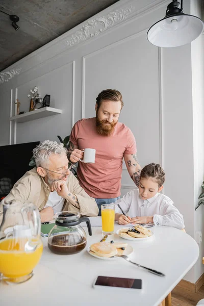 Padres Gay Mirando Niño Preadolescente Escribiendo Cuaderno Cerca Del Desayuno —  Fotos de Stock