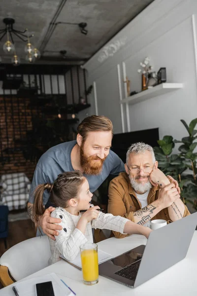Cheerful Gay Parents Looking Laptop Daughter Drinks Home — Stock Photo, Image