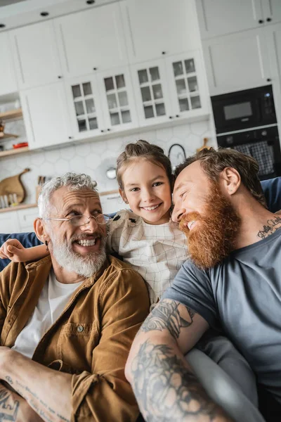 Positive Tattooed Same Sex Parents Sitting Preteen Daughter Couch Home — Stock Photo, Image