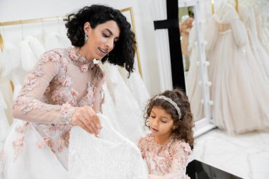 Esmer, ortadoğulu gelinlik giyip beyaz tül kumaşlar, hazırlık süreci, birliktelik gibi küçük tatlı kızı için gelinlik seçmeye yardım ediyor. 