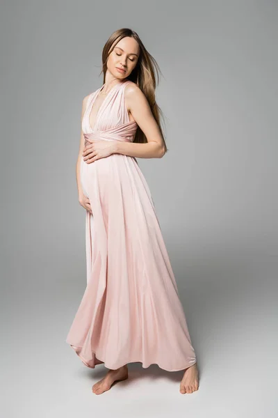 Pembe Elbiseli Rahat Yalın Ayaklı Hamile Bir Kadın Gri Arka — Stok fotoğraf
