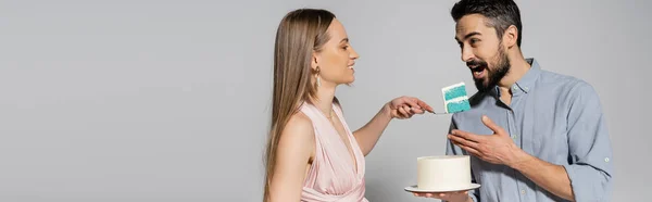 灰色の背景に性別パーティーのお祝いの間に夫の近くに青いケーキを保持陽気でエレガントな女性 親の概念を期待 それは男の子です バナー — ストック写真