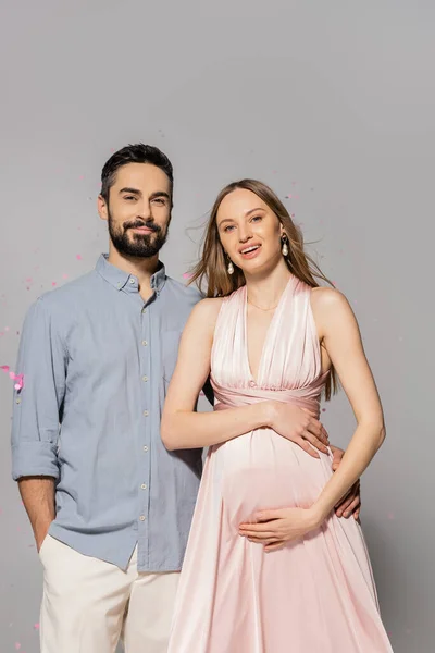 Pozitivní Muž Objímání Elegantní Těhotné Ženy Šatech Při Pohledu Kameru — Stock fotografie