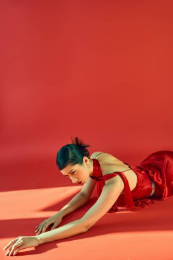 Şehvetli Asyalı kadın moda saç stili ve kalın makyajlı, atkı ve zarif elbisesiyle kırmızı arka planda ışık, moda bahar konsepti, z nesli