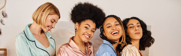 Позитивные многонациональные девушки в красочной пижаме, смотрящие в камеру и стоящие рядом друг с другом во время пижамной вечеринки дома, время сближения в удобной сонной одежде, культурное разнообразие, баннер 