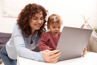 Çoklu görev yapan kadın, serbest çalışan, modern çalışan ebeveyn, iş ve hayatı dengelemek, rahat oturma odasında dizüstü bilgisayar kullanan mutlu kadın, modern ebeveynlik, başarılı bir kariyer inşa etmek, 