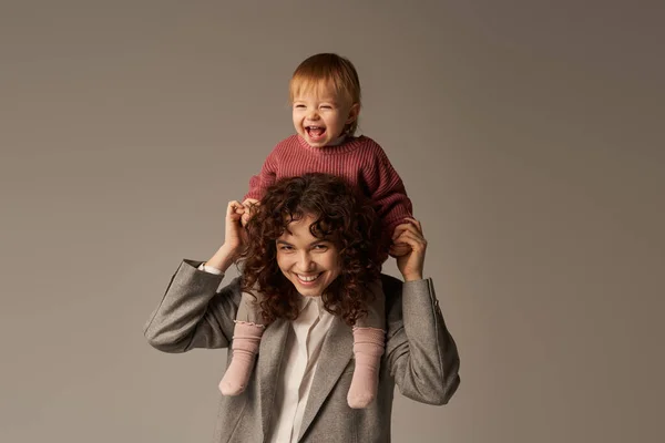 兴奋的肩上孩子 工作生活平衡 快乐的工作母亲 灰色背景的女人和快乐的女儿 工作生活和谐的概念 爱母性 高质量的家庭时间 — 图库照片
