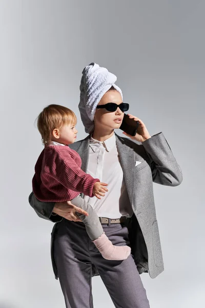 Llamada Telefónica Multitarea Mujer Gafas Sol Sosteniendo Brazos Hija Pie —  Fotos de Stock
