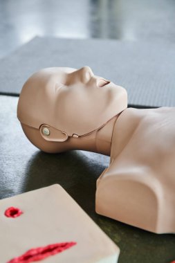 cardiopulmonary resuscitation training manikin near wound care simulator on floor in training room, medical equipment for first aid training and skills development clipart