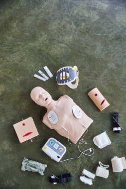 top view of CPR manikin, automated defibrillator, wound care simulators, compression tourniquets, neck brace and bandages, medical equipment for first aid training and skills development clipart