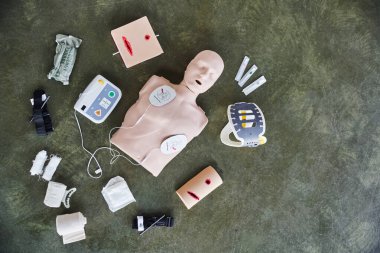 Suni teneffüs manikürü, otomatikleştirilmiş dış defibrilatör, yara bakım simülatörleri, sıkıştırıcı turnikeler, bandajlar ve şırıngalar, tıbbi ekipmanlar ve ilk yardım eğitimi konsepti.