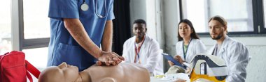 professional paramedic doing chest compressions on CPR manikin near multiethnic students in white coats during first aid seminar, acquiring and practicing life-saving skills concept, banner clipart