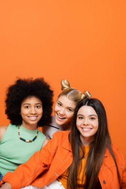 Kalın makyajlı şık çok ırklı kız arkadaşlarının yanında kameraya bakan pozitif sarışın genç kız turuncu, havalı ve kendine güvenen çok kültürlü genç kızlar, çeşitli ırklar 