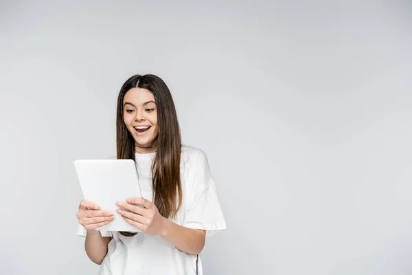 Ενθουσιασμένη Μελαχρινή Έφηβη Λευκό Shirt Χρησιμοποιώντας Ψηφιακό Tablet Ενώ Στέκεται — Φωτογραφία Αρχείου
