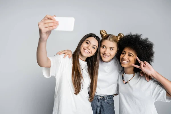 Glimlachende Tienervriendinnen Witte Shirts Knuffelen Gebaren Terwijl Selfie Nemen Smartphone — Stockfoto