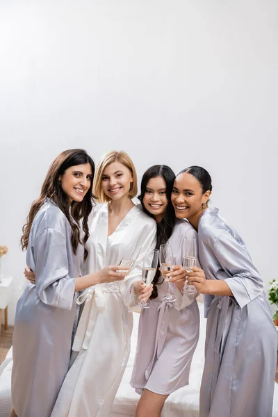 stock image bridal shower, multicultural girlfriends holding glasses with champagne, celebration before wedding, brunette and blonde women, bride and her bridesmaids, diverse ethnicities, looking at camera