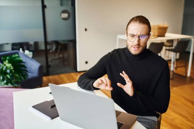 Siyahi balıkçı yaka ve gözlüklü ciddi bir girişimci çağdaş ofis, iş hayatı konsepti, bilgisayar üzerinde video görüşmesi yaparken el kol hareketi ve konuşma yapıyor.