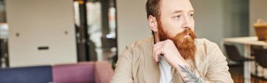 portrait of thoughtful, bearded and tattooed entrepreneur looking away in modern office environment, professional headshot,  business lifestyle concept, banner with copy space clipart
