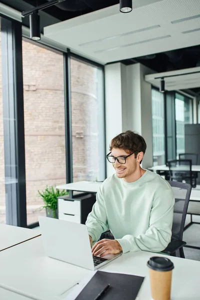 Fröhlicher Unternehmer Stylischer Brille Und Lässiger Kleidung Modernen Arbeitsplatz Sitzend — Stockfoto