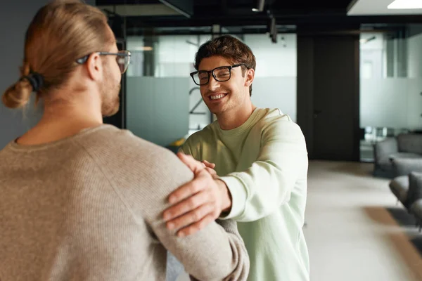 穿着休闲装 戴眼镜的快乐商人与同事握手 轻抚肩膀 同时确认了在现代合作空间的交易 成功的合作理念 — 图库照片