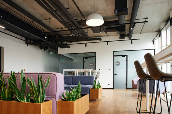 зона ожидания с зелеными растениями, удобный и уютный диван, высокий стол и стулья, высокотехнологичный стиль интерьера, коворкинг среды, концепция организации рабочего пространства
